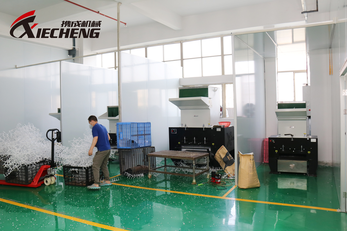 Trabalhadores alimentando manualmente as sobras em um granulador central.